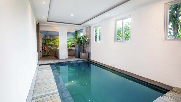 A modern indoor swimming pool with clear water, surrounded by white walls and large windows. - Eco Boo Boo - Green Genesis (Jimbaran)