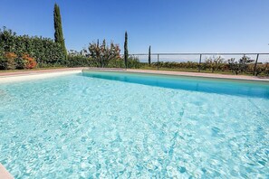 A clear swimming pool with a fenced area, surrounded by trees and a clear sky. - Villa Campoluce: A welcoming two-story villa in a quiet position, in the Marche countryside, at a short distance from the sea, with Free WI-FI. (Cupra Marittima)