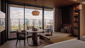 Ein modernes Hotelzimmer mit einem großen Balkon, einem runden Esstisch und einer gemütlichen Sitzecke.