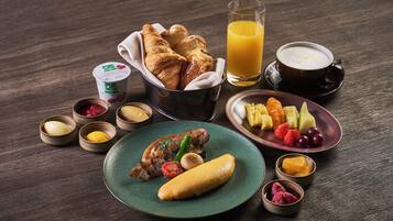 A breakfast setting with croissants, fruit, a banana, and a cup of coffee.