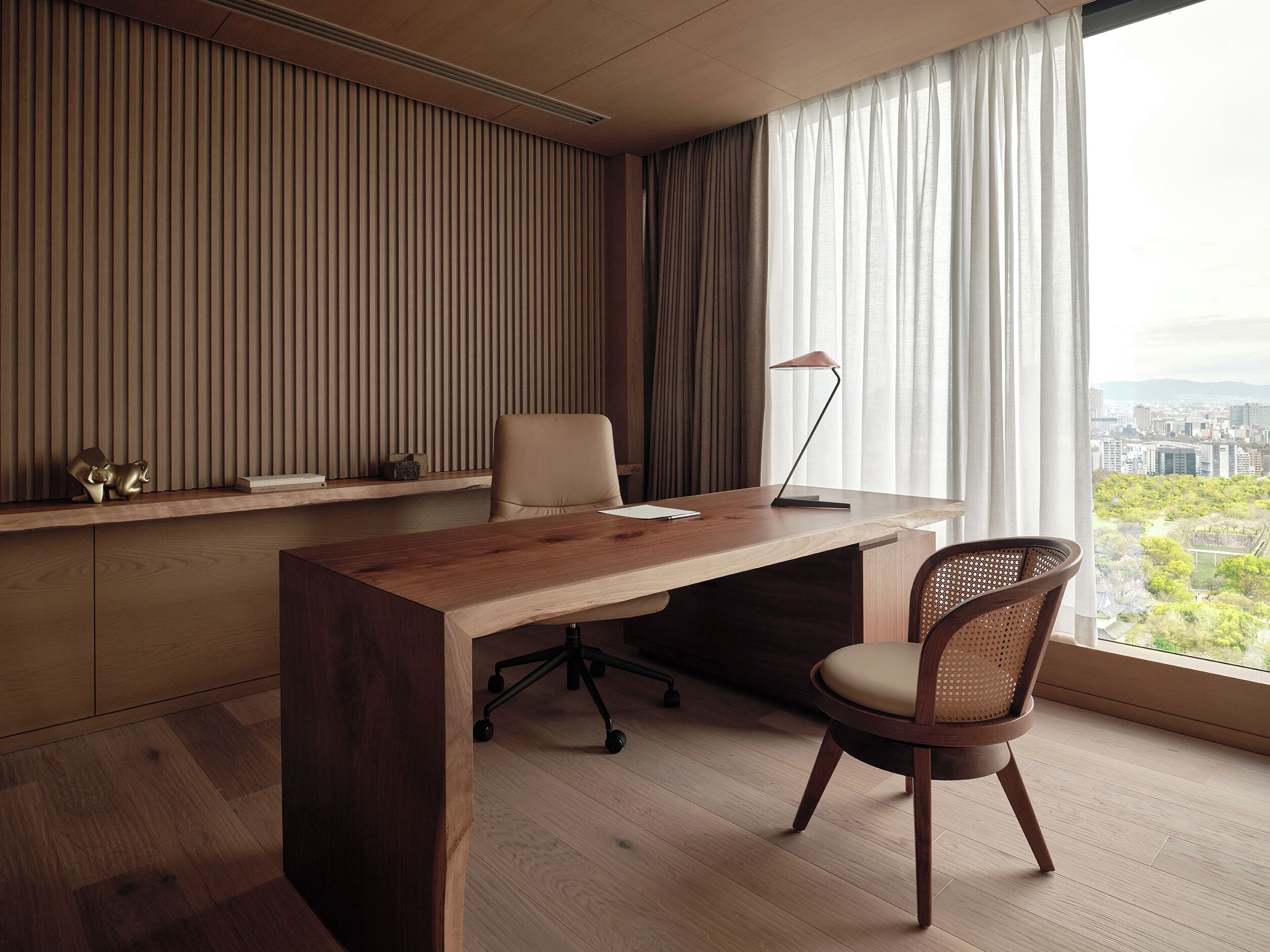 A modern office space with a wooden desk, a chair, and a lamp.