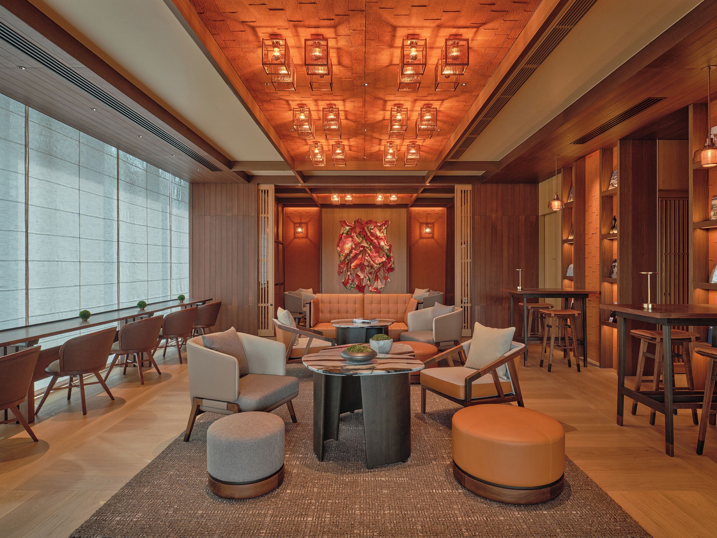 A modern lounge area with a wooden ceiling, large windows, and a central seating arrangement.