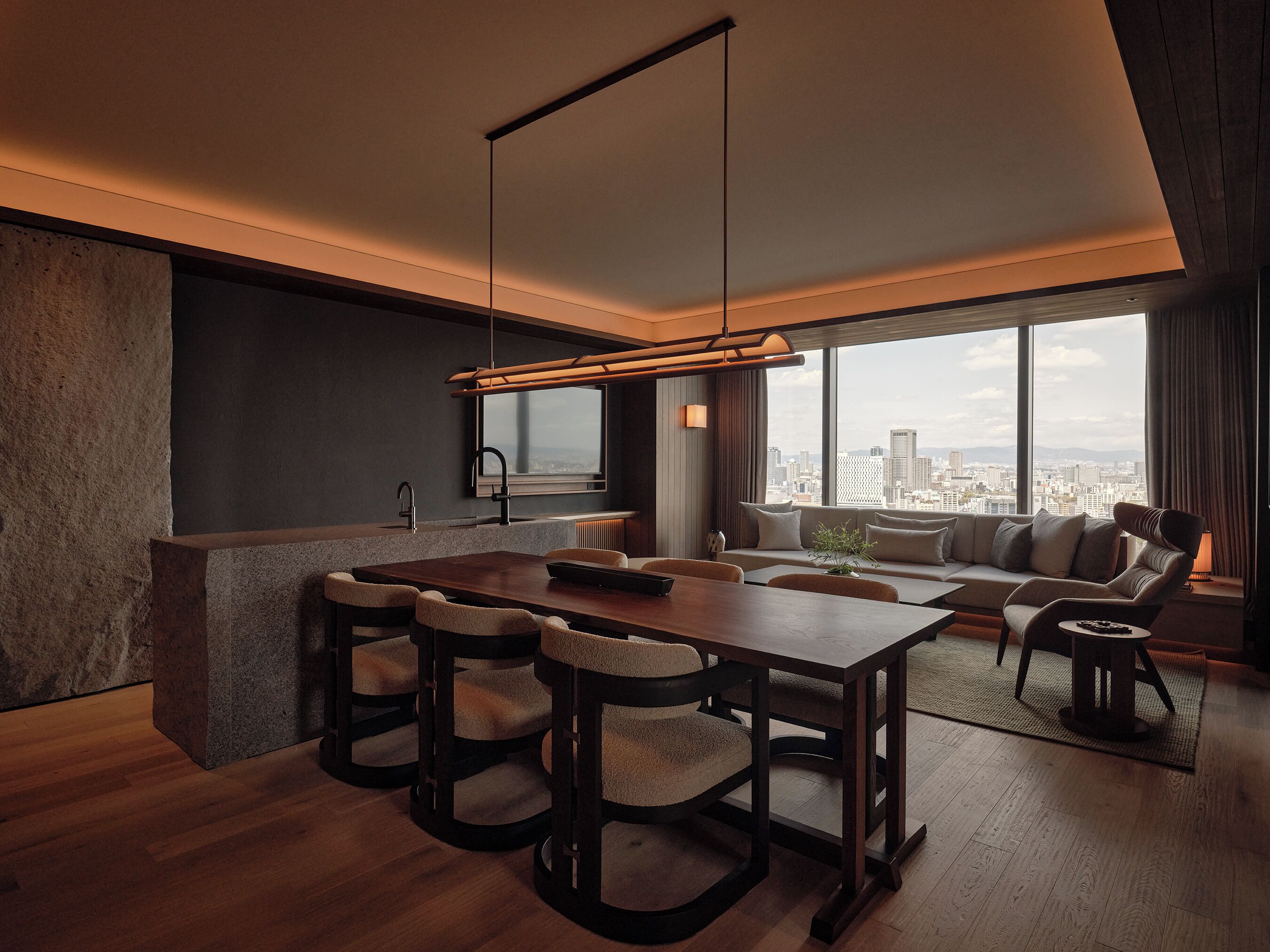 A modern kitchen with a dining area, large windows, and a city view.