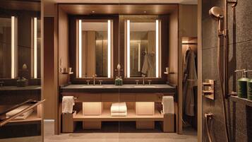 A modern bathroom with a double sink vanity, large mirrors, a glass-enclosed shower, and a towel rack.