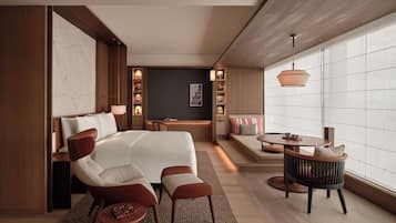 A modern hotel room with a large bed, a seating area with a table, and a view of the city through large windows.