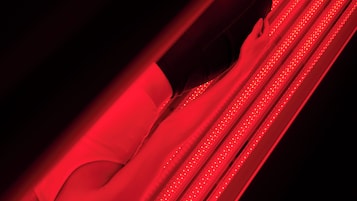 A person lying on a red-lit surface with a curved structure.