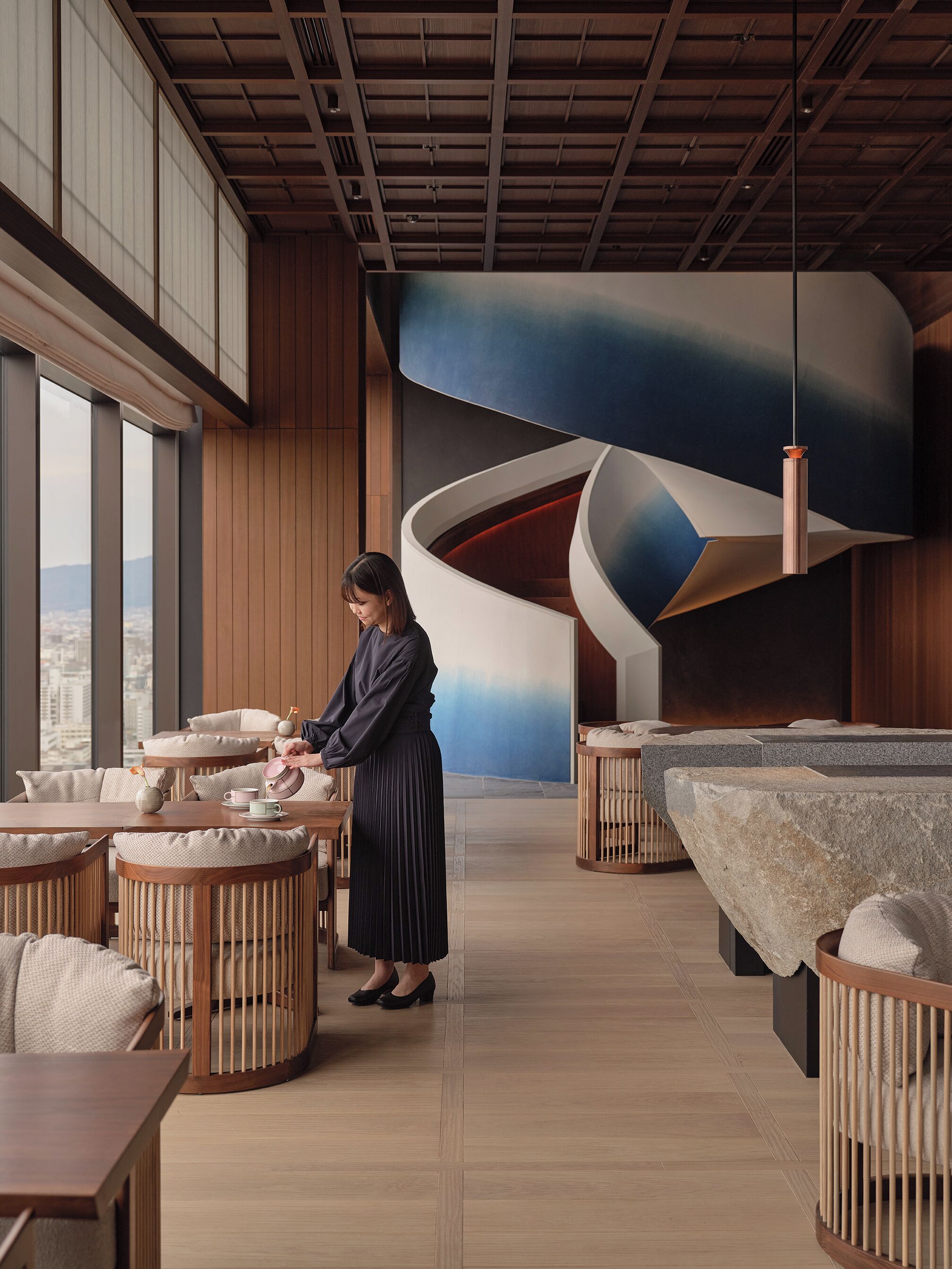 A modern interior with wooden floors, round tables, and a unique curved wall design.