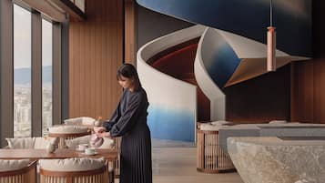 A modern interior with wooden floors, round tables, and a unique curved wall design.