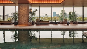 Ein moderner Poolbereich im Innenbereich mit Blick auf eine Stadtlandschaft durch große Fenster.