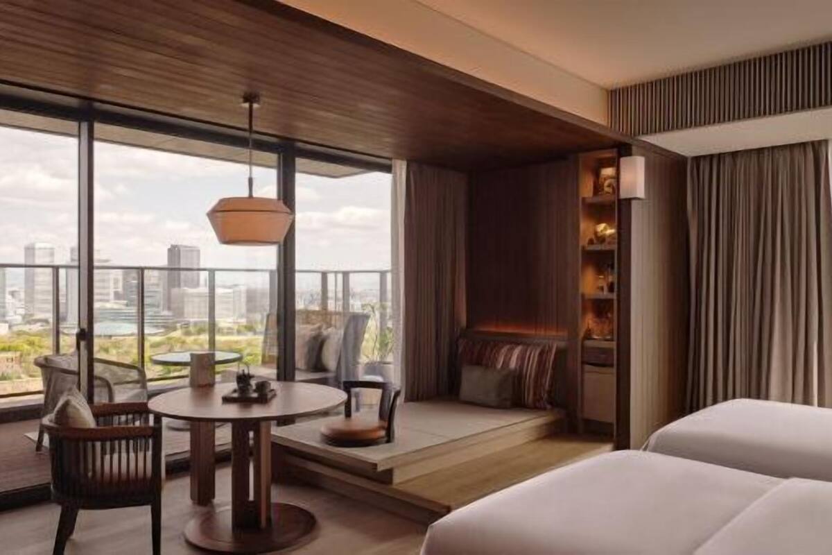 A modern hotel room with a large balcony, a round table, and seating area.