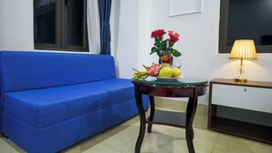 A room with a blue sofa, a small table with a glass top, a lamp, and a window with curtains. - Hanoi Shining House (Hanoi)