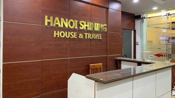 A reception desk with a wooden panel wall behind it, displaying the text "HANOI SHING HOUSE & TRAVEL". - Hanoi Shining House (Hanoi)