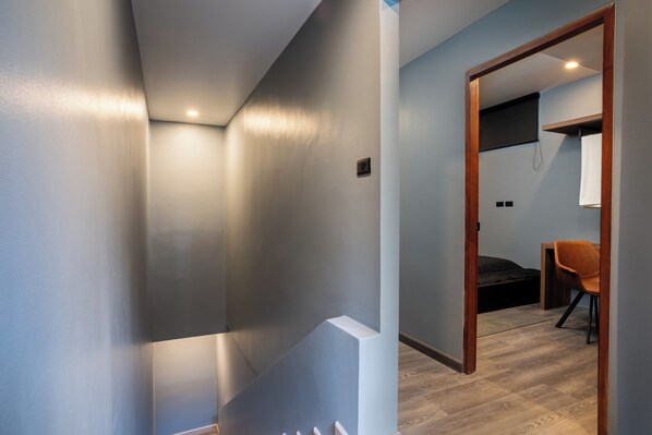 A modern room with a wooden floor, a bed, a chair, and a small desk. - 3 Double U - Kalim Sea View (Patong)