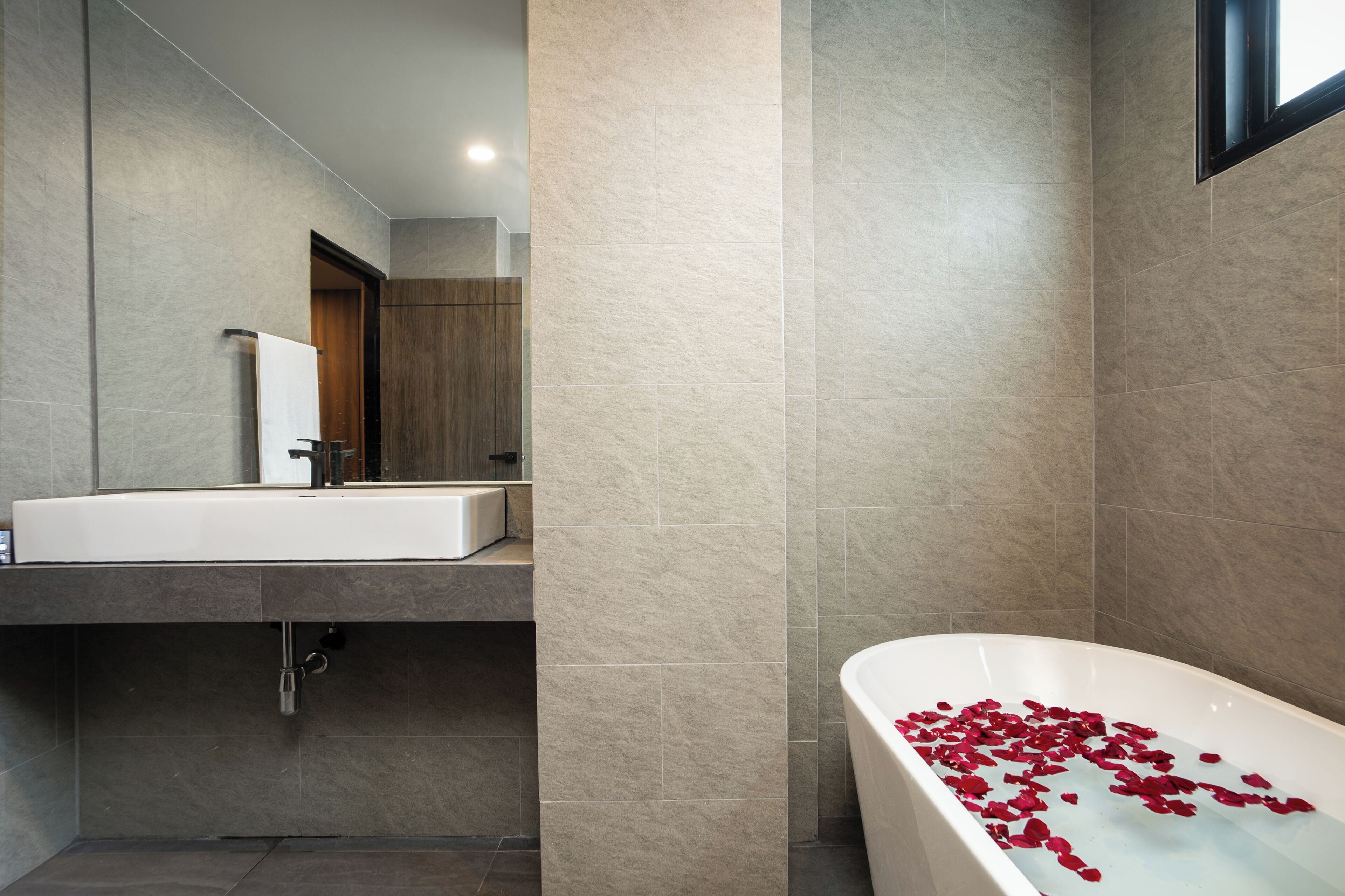 Une salle de bain moderne avec une grande baignoire, un lavabo et un miroir.