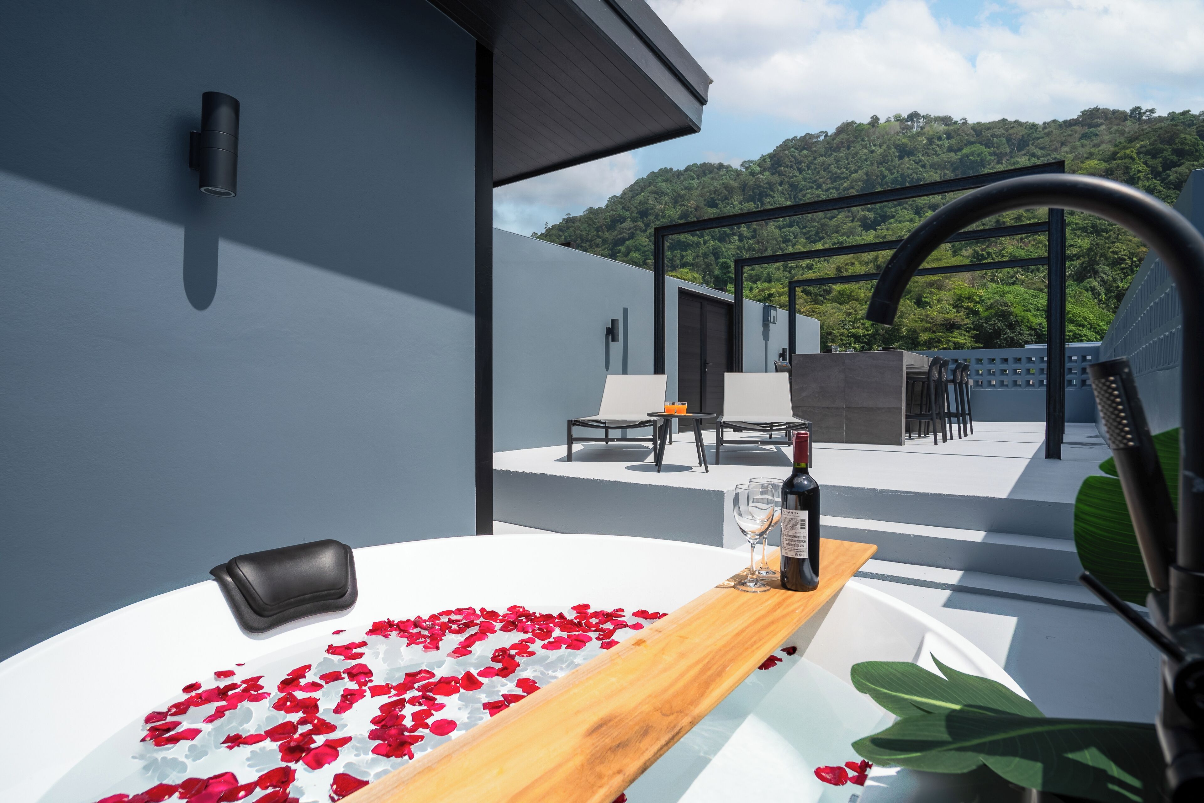A modern outdoor seating area with a pool, surrounded by a mountain view.