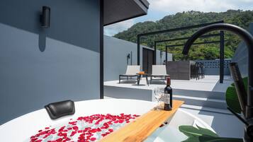 A modern outdoor seating area with a pool, surrounded by a mountain view.