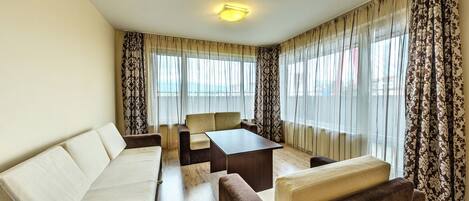 A modern living room with a sofa, armchairs, a coffee table, and a dining table.