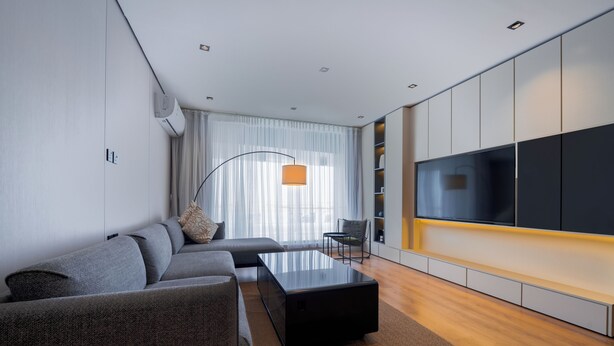 A modern living room with a sofa, coffee table, TV, and a large window with curtains. - Arjan Park Al Narjis (Riyadh)