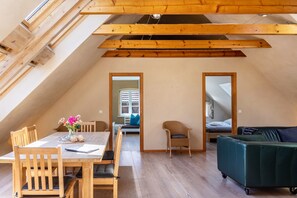 Une pièce de style loft avec un plafond en bois, une table à manger avec des chaises, un canapé et un lit.