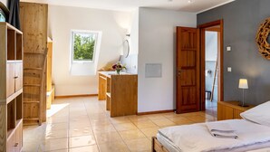 Un dormitorio con cama, muebles de madera, una ventana y una puerta.