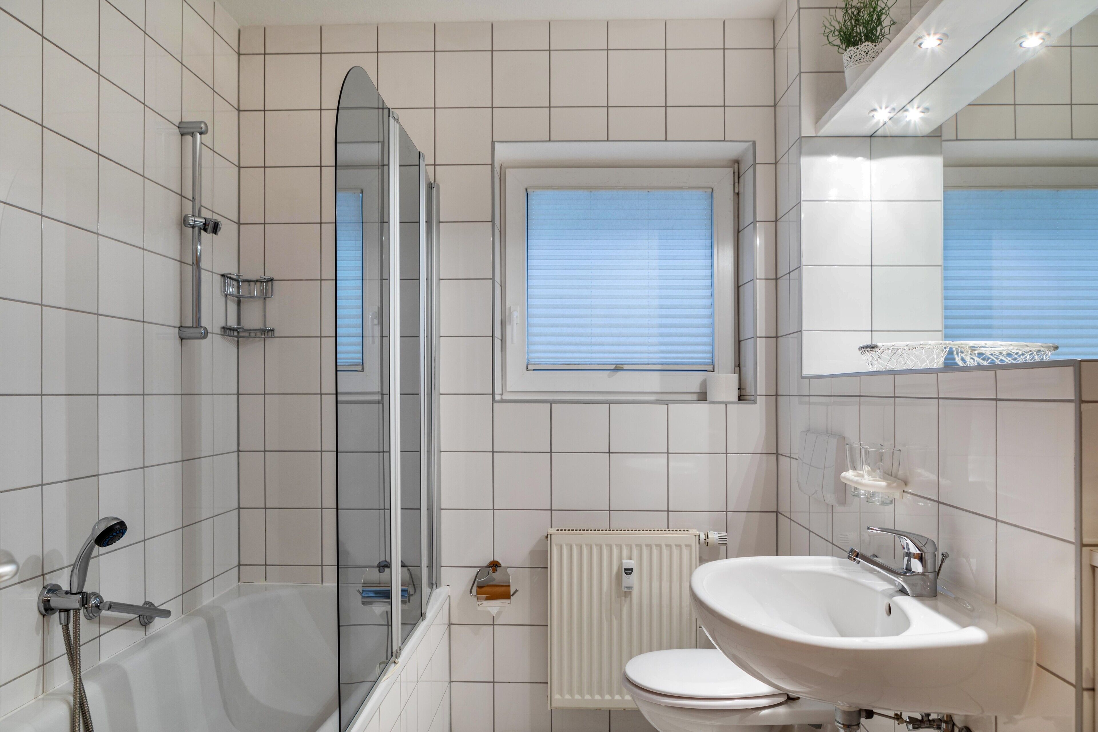 A modern bathroom with a bathtub, shower, toilet, and sink.