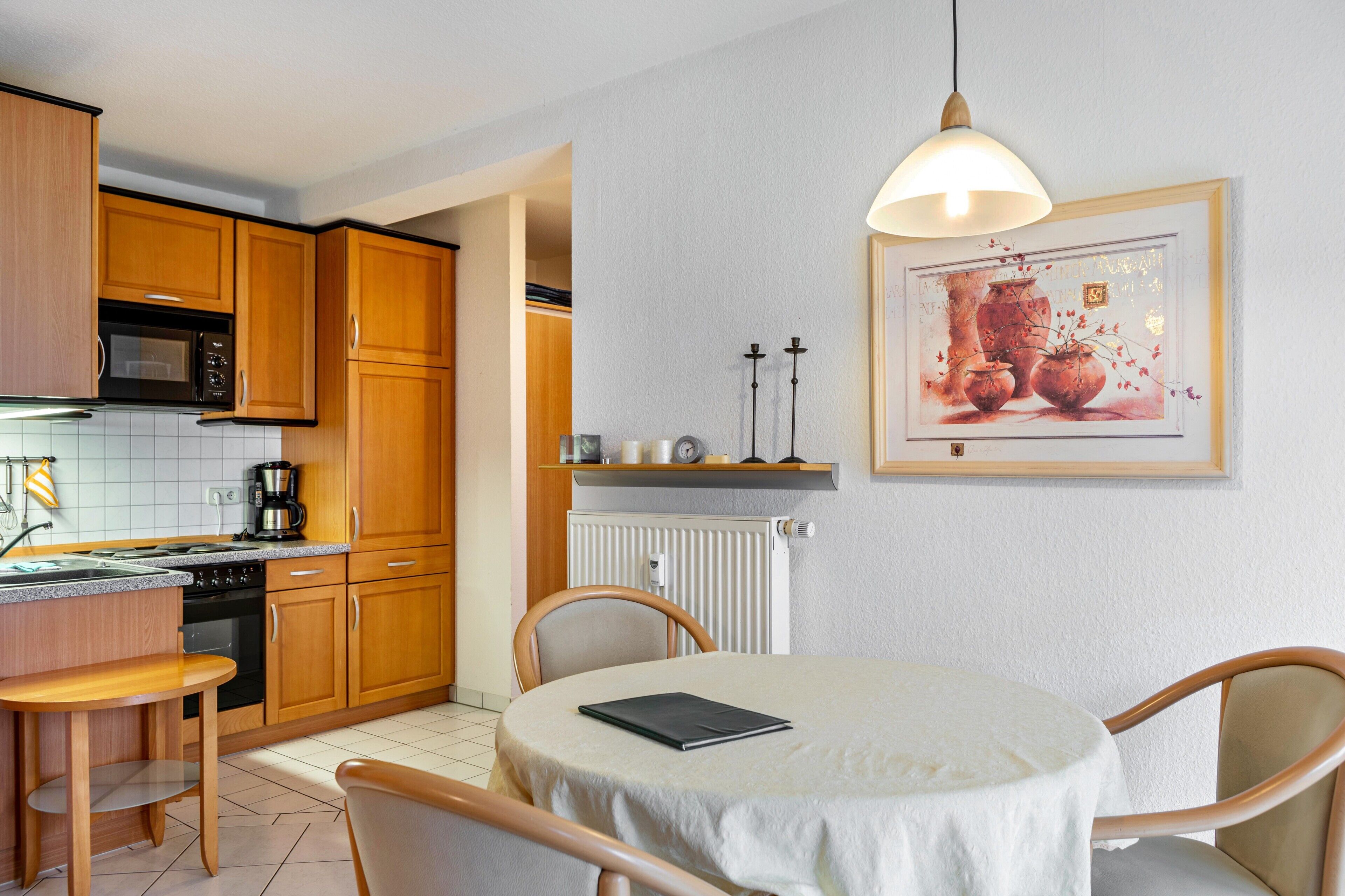 Una cocina con armarios de madera, microondas y una mesa de comedor con sillas.