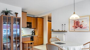 Una cocina con armarios de madera, una mesa de comedor con sillas y una lámpara colgante.