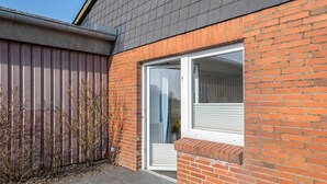 Un immeuble résidentiel avec une façade en briques, une porte-fenêtre coulissante et une clôture en métal.