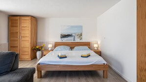 Une chambre à coucher avec un lit en bois, deux tables de chevet avec des lampes, une grande armoire en bois et un tableau accroché au mur.