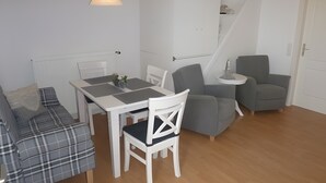 En kompakt opholdsstue med spisebord, sofa, stol og lille sofabord.