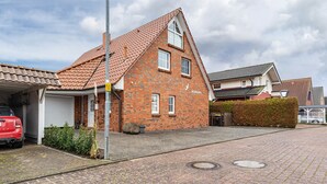 A residential building with a red-tiled roof, a garage, and a paved driveway. - Apartment ''dat Rode Huus' - Ferienwohnung' with Private Terrace, Private Garden and Wi-Fi (Kronsgaard)