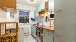 A kitchen with a built-in oven, a sink, and a window with a view of greenery. - Apartment ''dat Rode Huus' - Ferienwohnung' with Private Terrace, Private Garden and Wi-Fi (Kronsgaard)