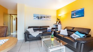 A living room with a sofa set, a coffee table, and a painting of a lighthouse on the wall. - Apartment ''dat Rode Huus' - Ferienwohnung' with Private Terrace, Private Garden and Wi-Fi (Kronsgaard)