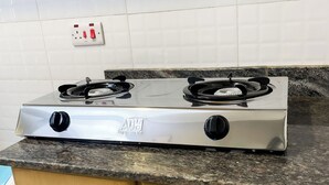 Een keuken met een roestvrijstalen fornuis, houten kastjes en een betegelde achterwand.