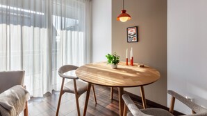 Una mesa de comedor redonda de madera con sillas, una lámpara colgante, una planta en maceta y un cuadro en la pared.