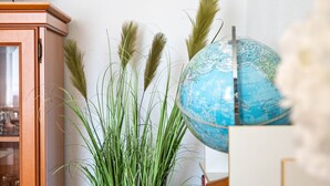 Un globe terrestre, un meuble en bois et de grandes plantes vertes.