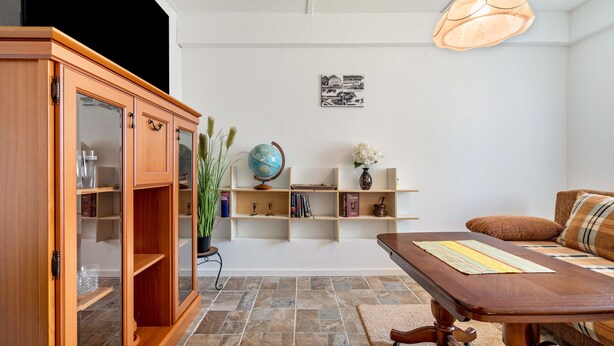 Un salon comprenant un meuble en bois, un globe terrestre, des étagères remplies de livres, un canapé et une table avec un set de table.