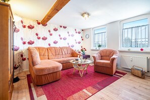Un salón acogedor con sofá, sillón y mesa de centro, un radiador y una ventana con cortinas.