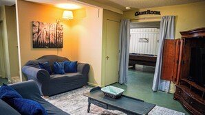 A living room with a sofa, a coffee table, a TV, and a painting on the wall. - Recently renovated, beautiful chalet just miles from Wild Animal Safari (Pine Mountain)
