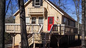 A wooden cabin with a red door, a balcony, and a sign indicating a price of $15. - Recently renovated, beautiful chalet just miles from Wild Animal Safari (Pine Mountain)