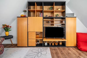 Una sala de estar moderna con un televisor de pantalla plana grande, estanterías de madera y un sofá rojo.