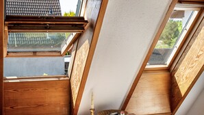 Kattoikkuna, jonka yhteydessä on puupalkkeja, kynttilä ja kori.