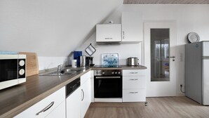 Una cocina moderna con armarios blancos, electrodomésticos de acero inoxidable y encimera de madera.