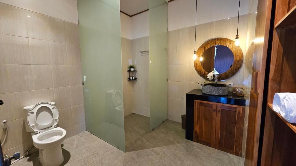 A modern bathroom with a toilet, a glass-enclosed shower, and a vanity with a mirror and sink.