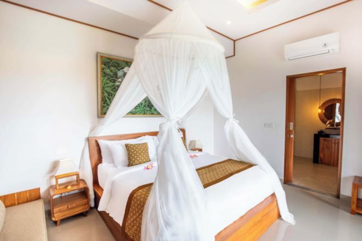 A hotel room with a bed, bedside table, and a mirror.