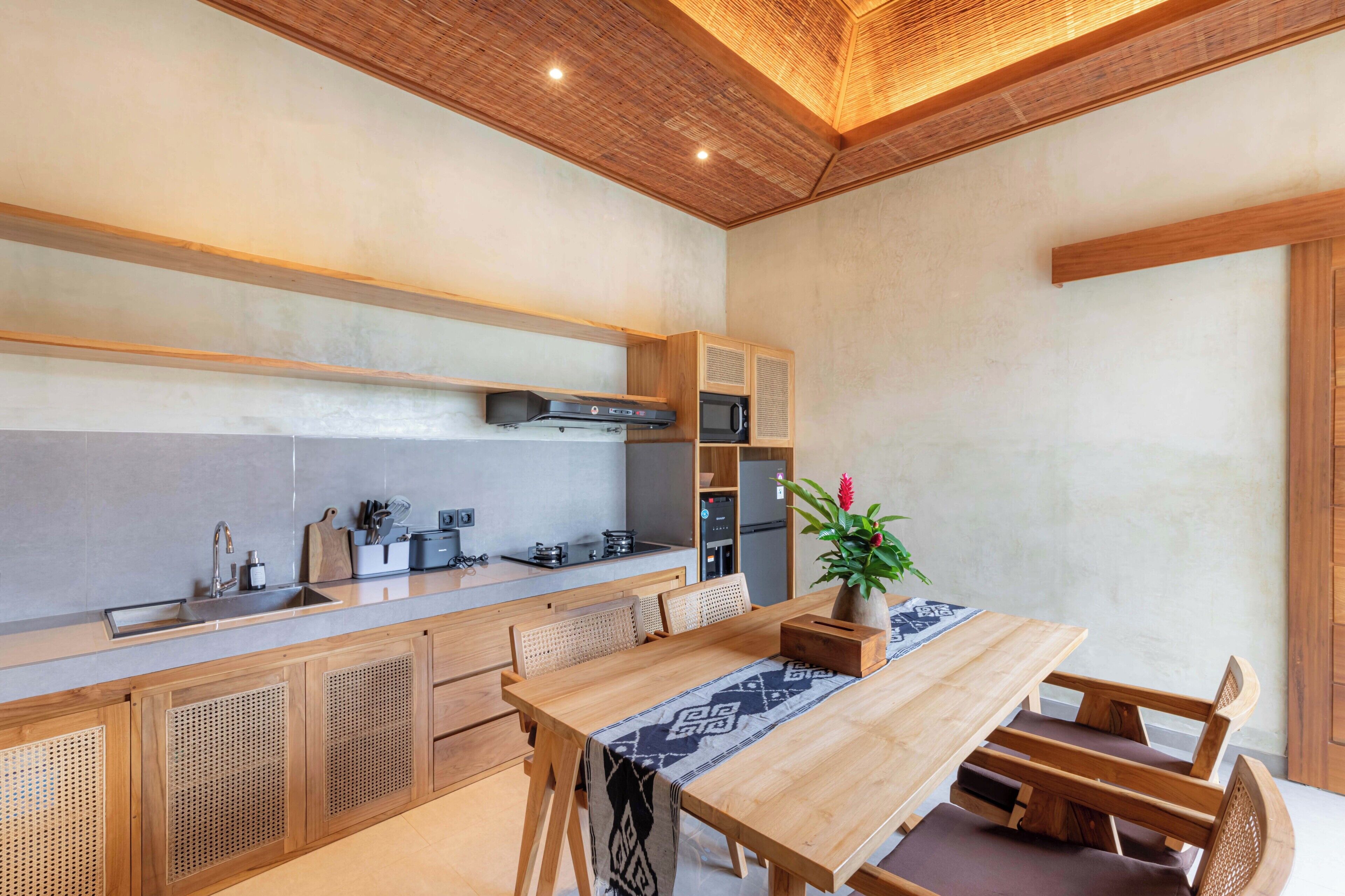 A modern kitchen with wooden cabinets, a built-in microwave, and a wooden dining table with benches.
