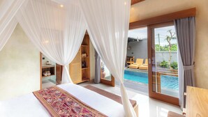 A bedroom with a large bed, a canopy, a view of a swimming pool, and a wooden shelf with towels. - Weda Villas (Ubud)