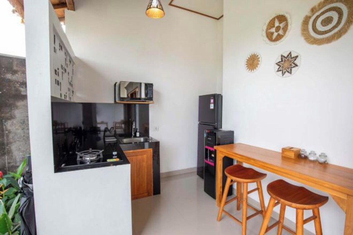 A compact kitchen with a stove, refrigerator, and wooden bar stools.