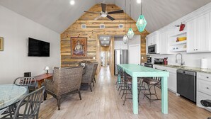 Een ruime keuken met een hoge plafond, houten balken en een centraal eiland.