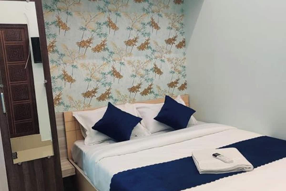 A bedroom with a bed, a wardrobe, and a floral-patterned wall.